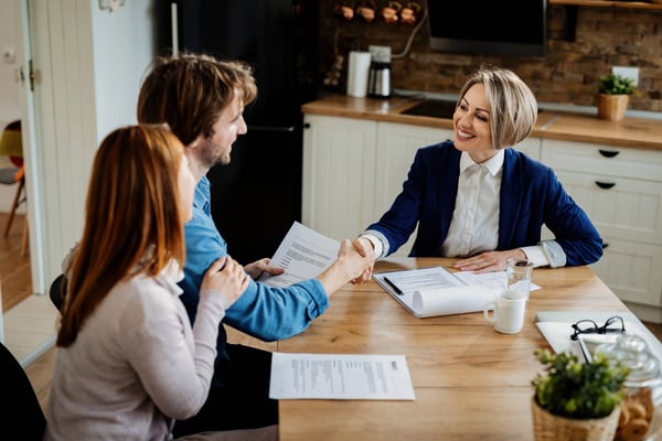 happy-insurance-agent-shaking-hands-with-young-couple-after-successful-meeting